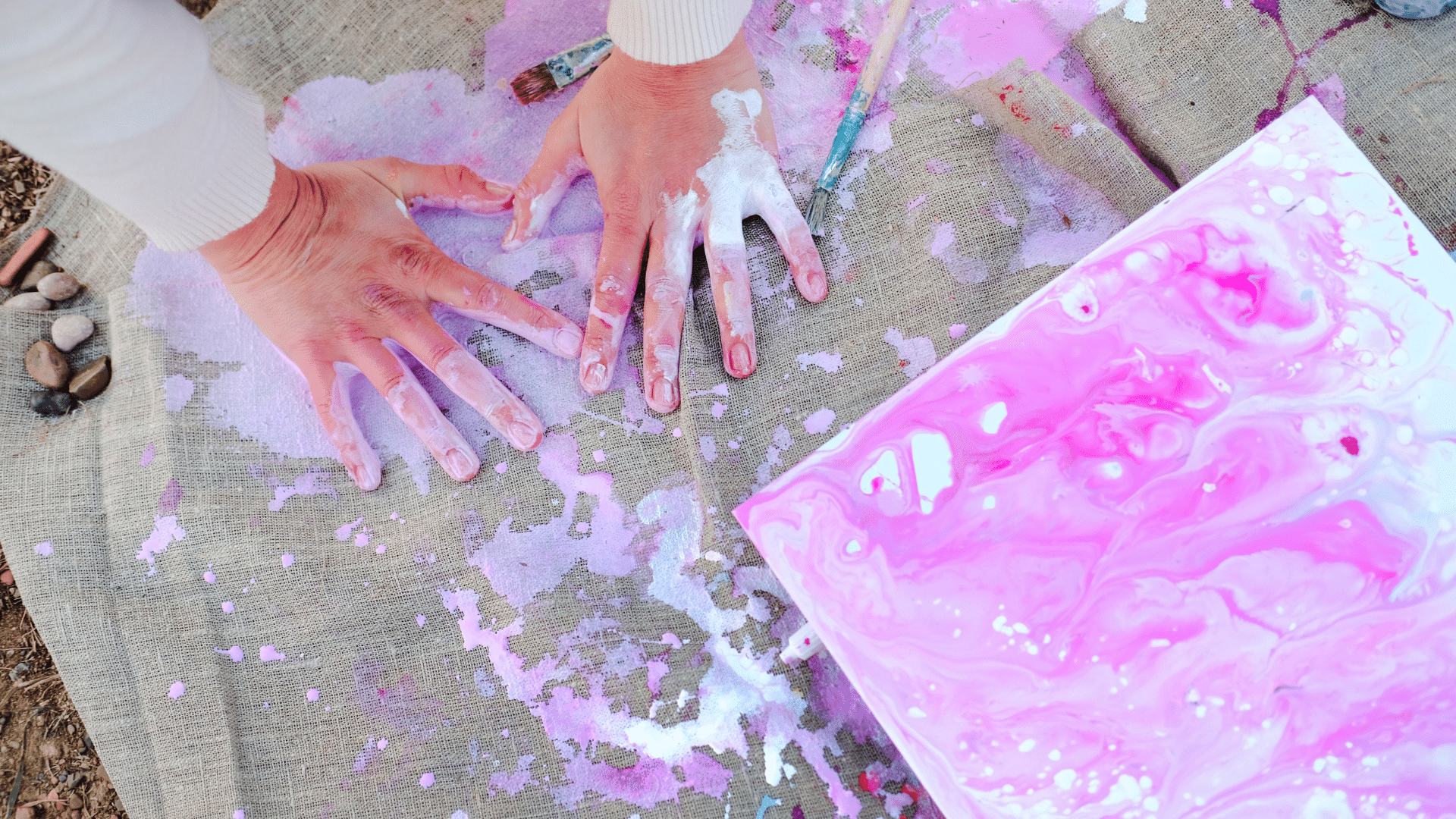 Kunsttherapie bei Krebs: farbige Hände neben bemalter Leinwand