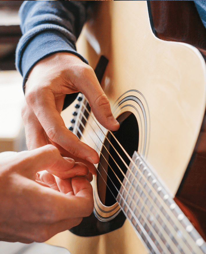 Musiktherapie bei Krebs: Hand von Krebspatient zupft an Gitarrensaite